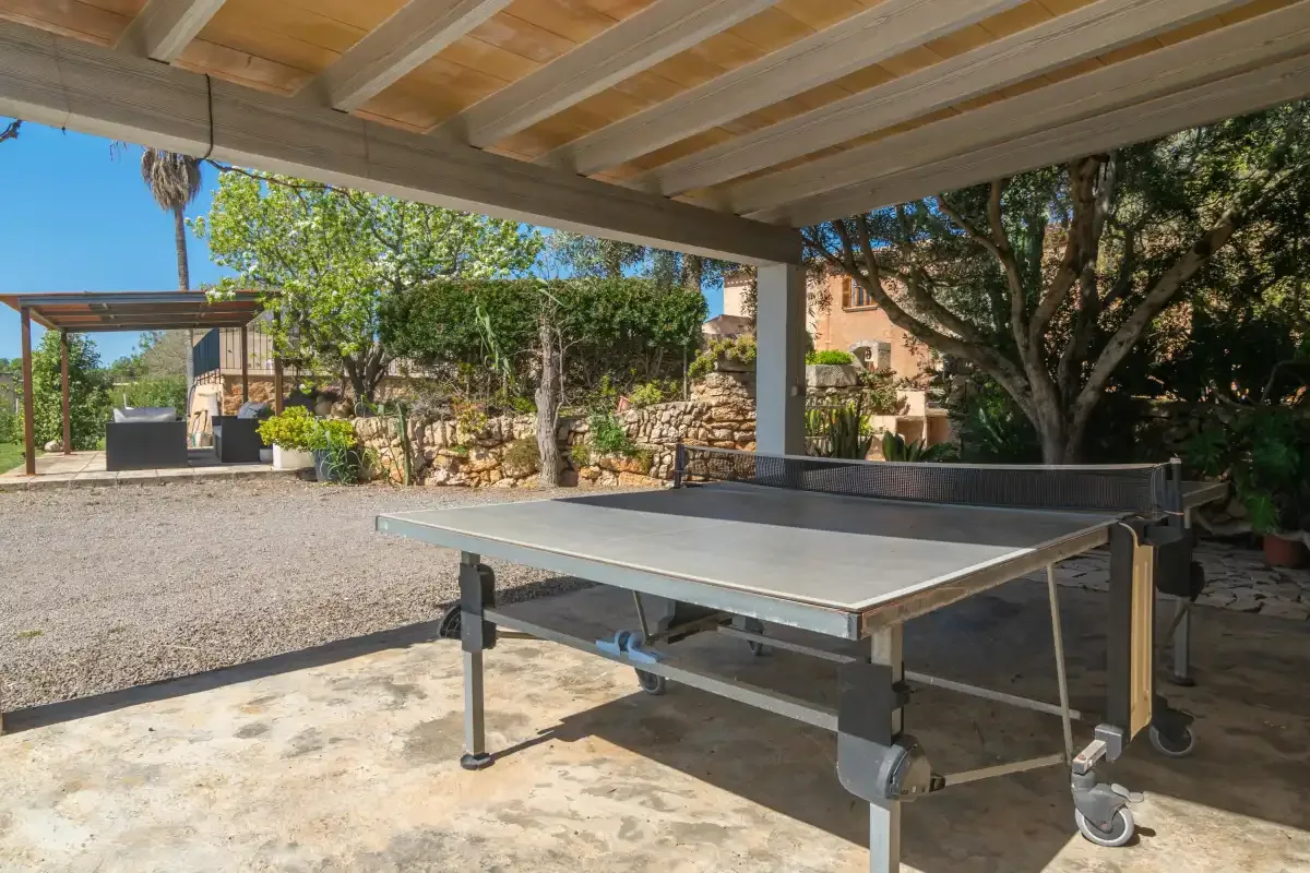 A covered outdoor area with a table tennis table and a gravel courtyard.