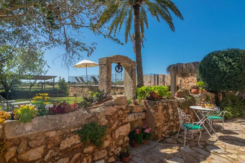 A stone garden patio with outdoor seating, plants, and a palm tree.