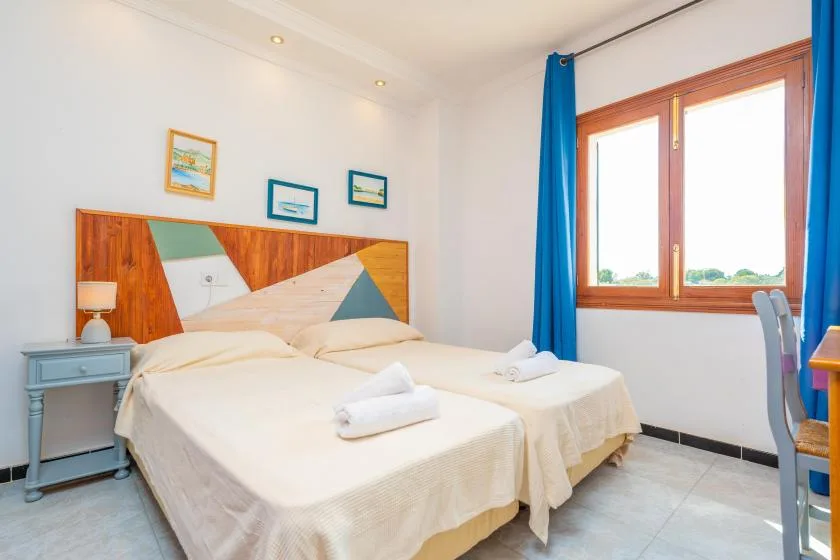 Un dormitorio con dos camas, una mesita de noche y una ventana con cortinas azules.