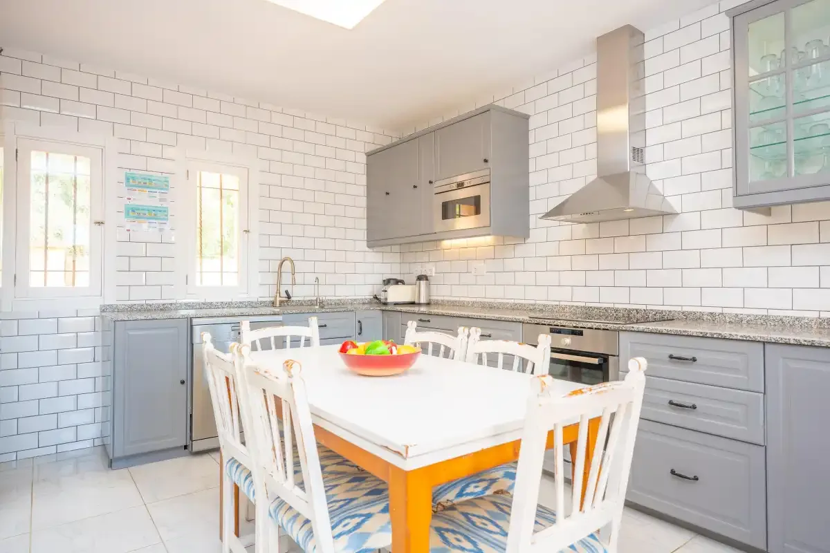 Una cocina luminosa con una mesa de comedor y sillas blancas.