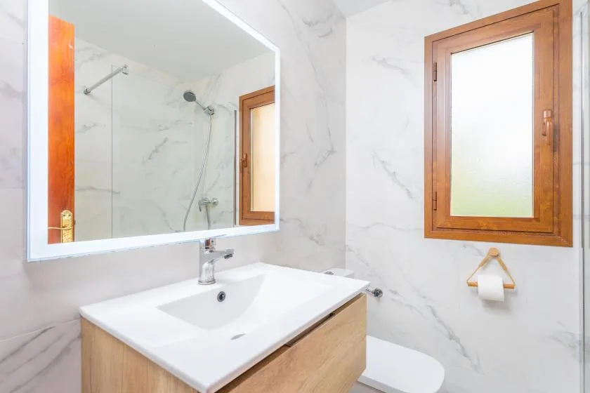 Un baño luminoso con lavabo, inodoro y ducha.