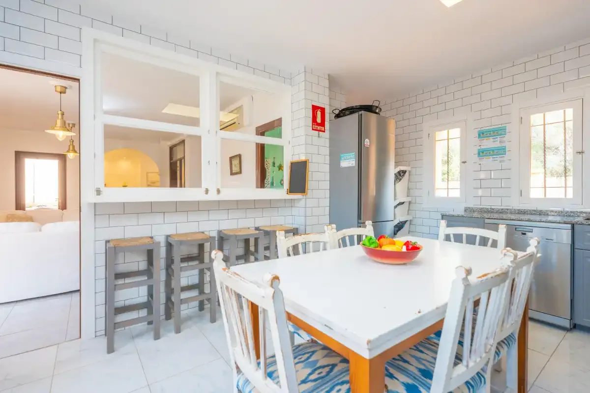 Una cocina luminosa con zona de comedor, mesa amplia y asientos junto a la encimera.