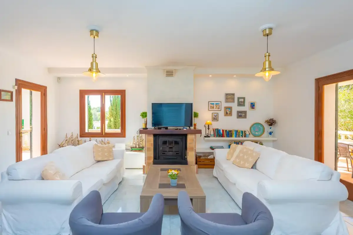 Un salón luminoso con asientos alrededor de una mesa de centro y una chimenea.