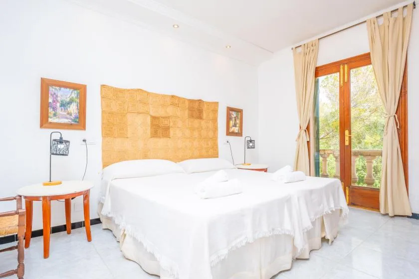 Un dormitorio con dos camas, mesitas de noche y puertas de vidrio que dan a un balcón.