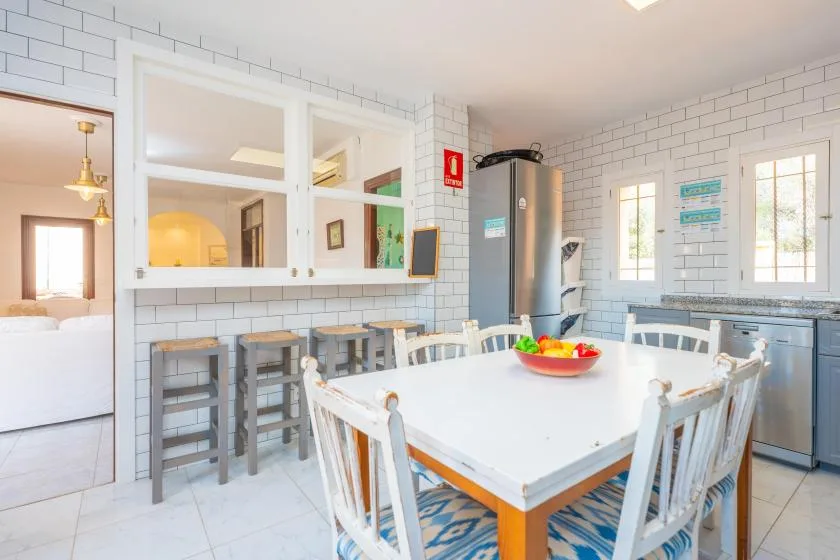 Un comedor luminoso con paredes de azulejos y una mesa grande junto a la cocina.