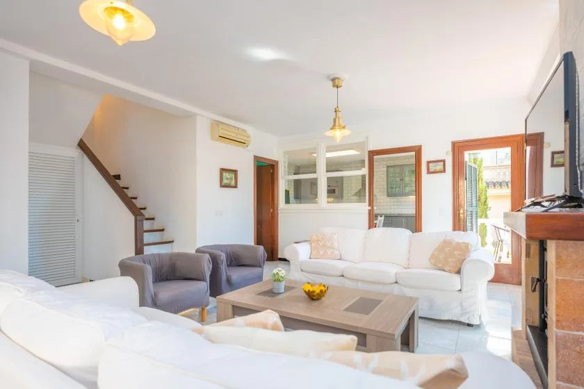 Una sala luminosa con asientos blancos, una mesa de centro y una escalera.