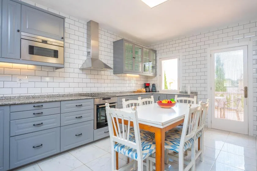Una luminosa cocina con comedor tiene una mesa y sillas junto a la encimera.