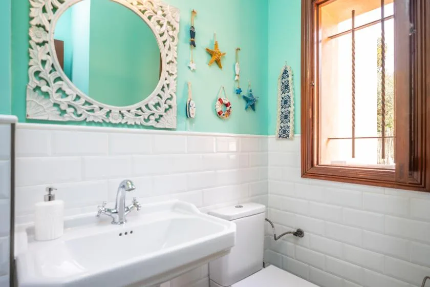Un baño luminoso con un lavabo blanco y una ventana.