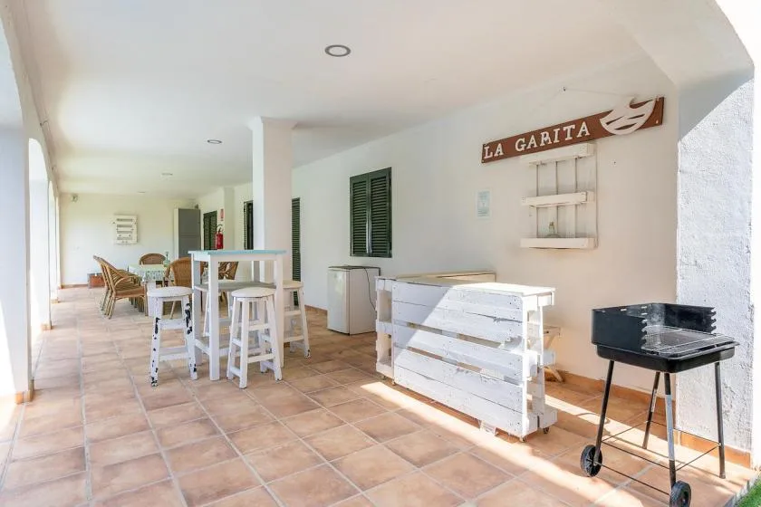 Una zona de comedor cubierta con mesas altas, bancos y una parrilla.
