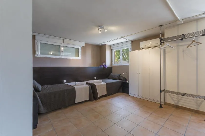 A bedroom with two beds, a wardrobe, and a freestanding clothes rack.