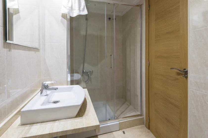 A bathroom with a sink beside a glass-enclosed shower.