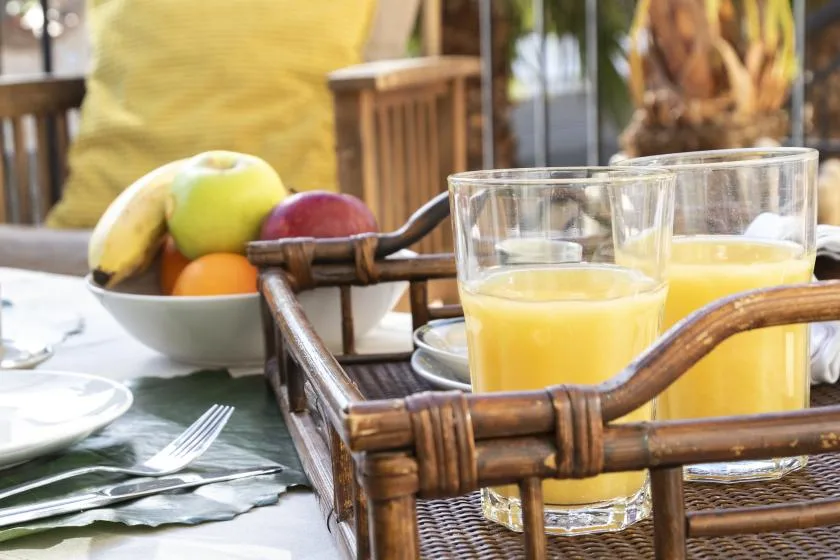 A breakfast table with glasses of orange juice and a bowl of fruit.