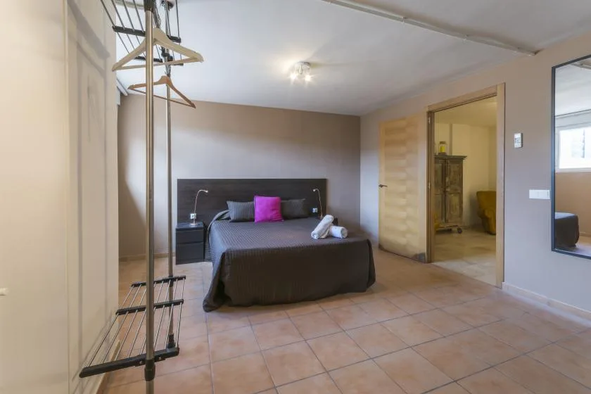 A bedroom with a double bed and a bright pink pillow.