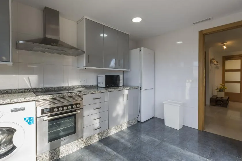 A modern kitchen with gray cabinets, a countertop, and built-in appliances.