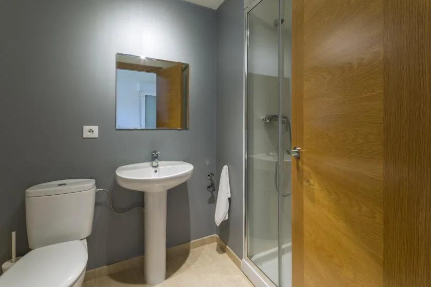 A bathroom with a pedestal sink, toilet, and glass shower.