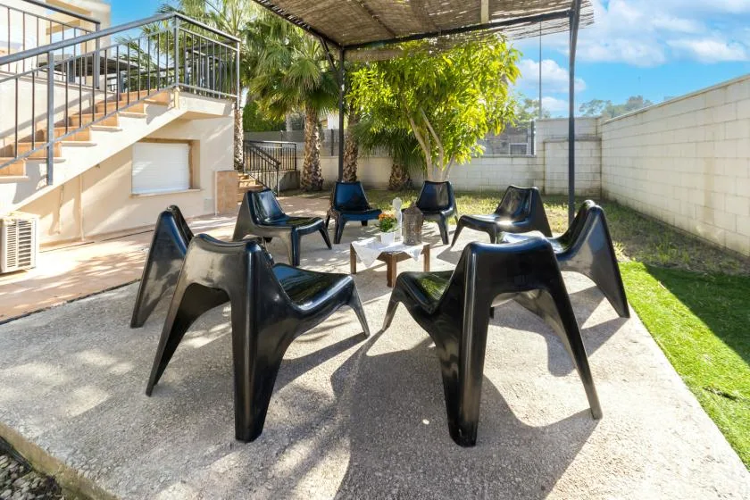 An outdoor patio seating area with black chairs around a small table beneath a canopy.