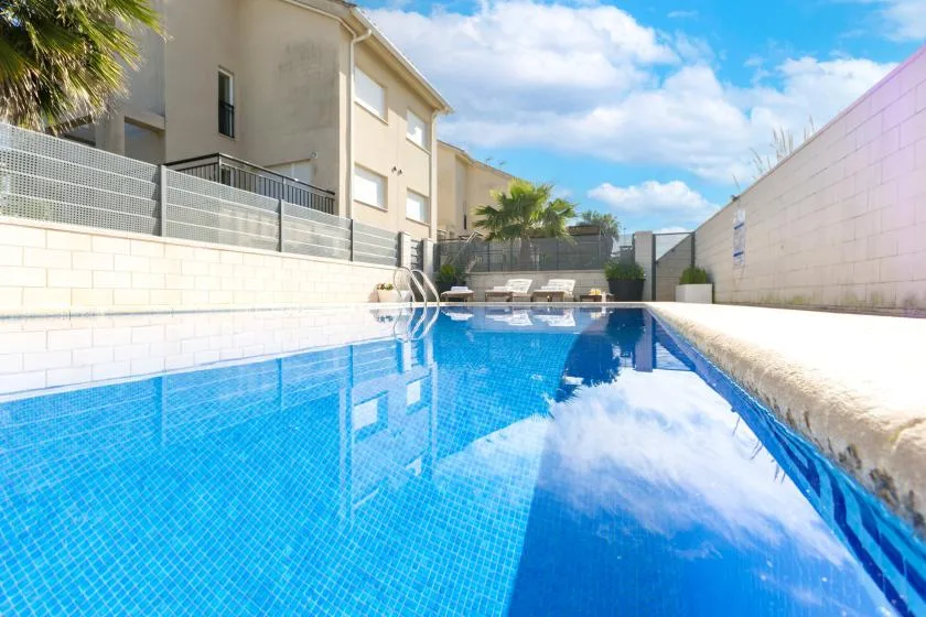 A swimming pool beside a building, with lounge seating at the far end.