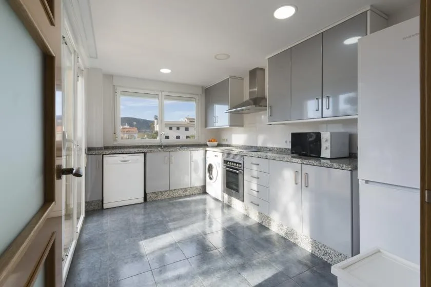 A bright modern kitchen with gray cabinets, a countertop, and a window.