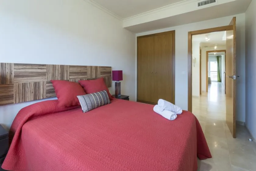 A bedroom with a red bed and an open doorway to a hallway.