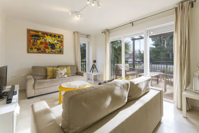 A bright living room with seating beside large glass doors opening onto a balcony.