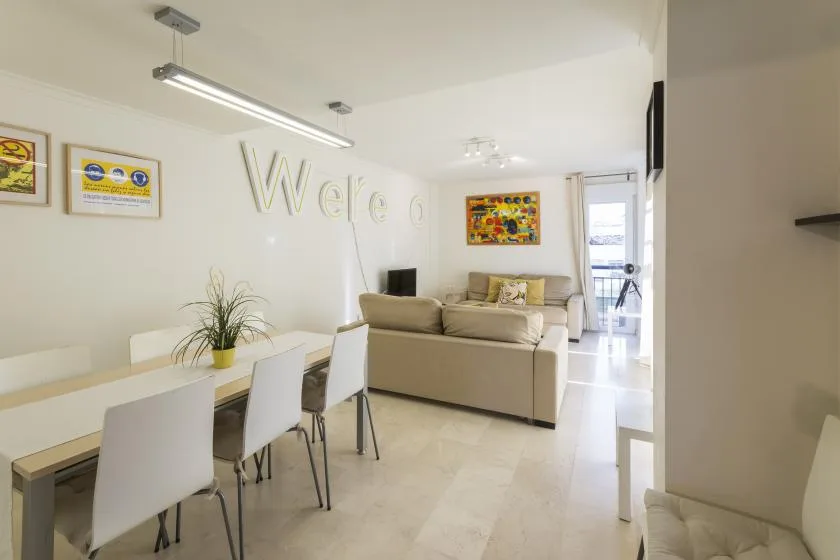 A bright living and dining area with a table, seating, and colorful wall art.