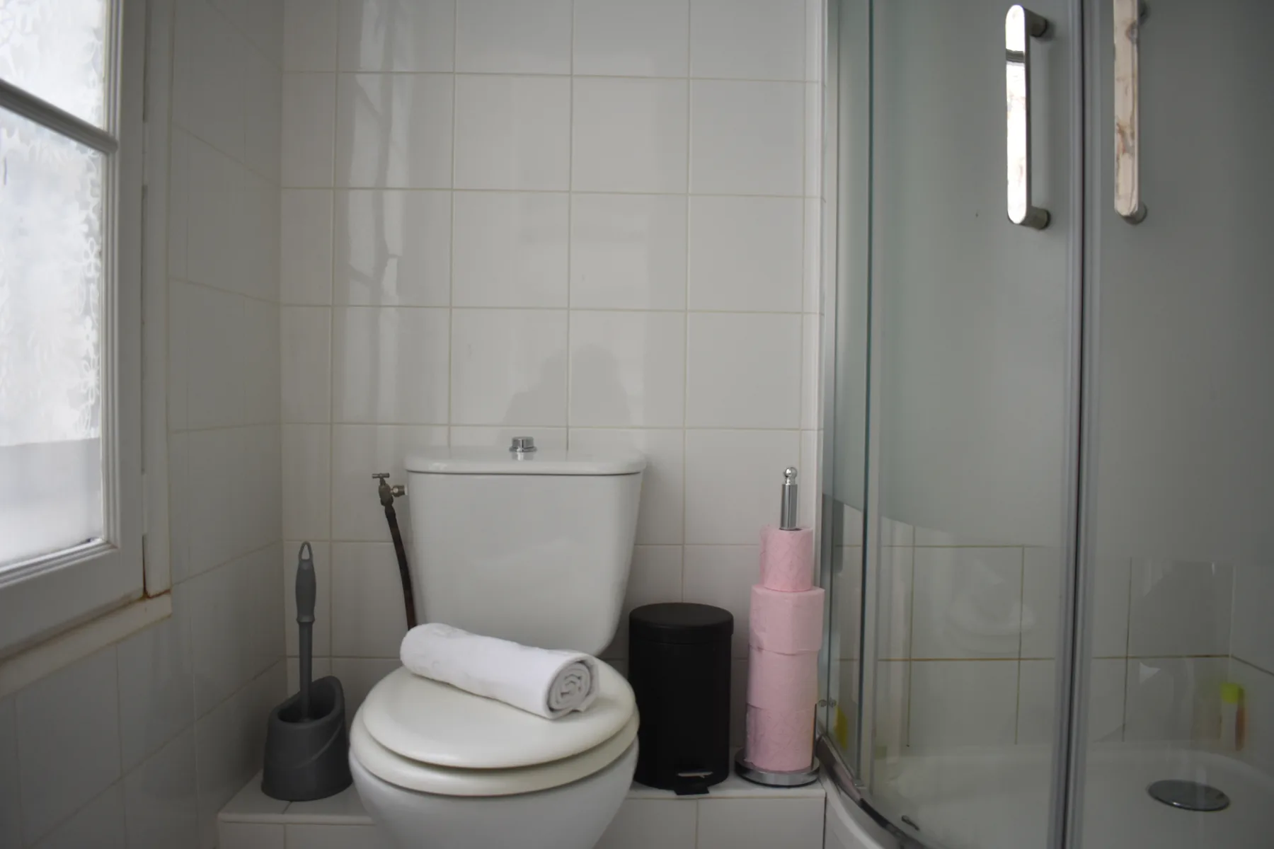 A tiled bathroom with a toilet beside a glass shower.
