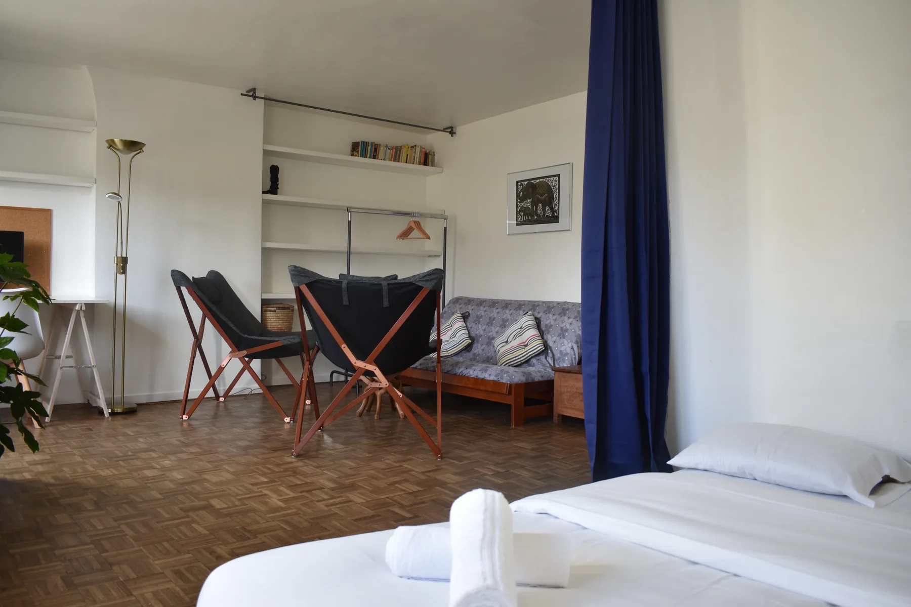 A bedroom with a bed in the foreground and seating by the wall.
