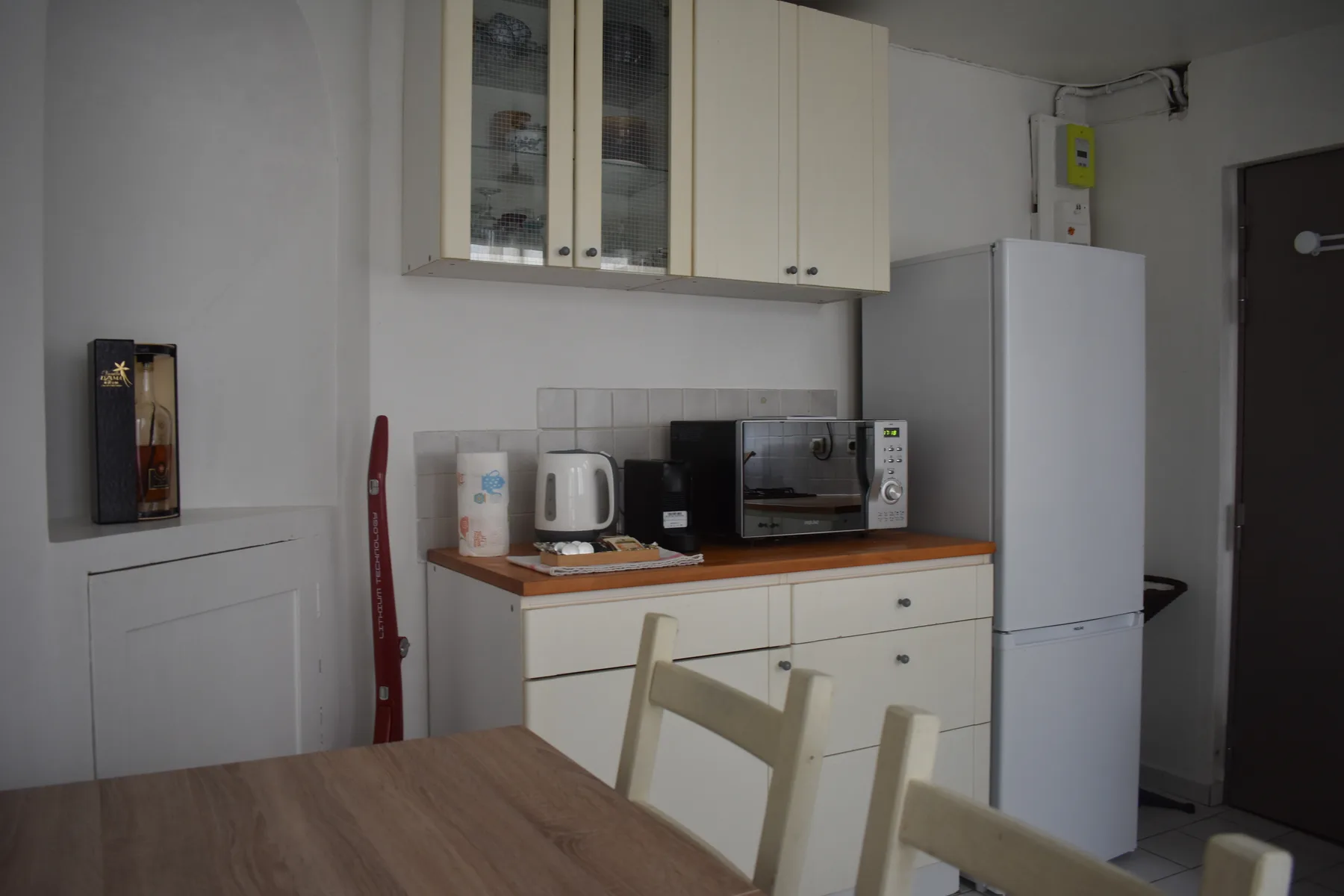 A compact kitchen with cabinets, a countertop, and a refrigerator.