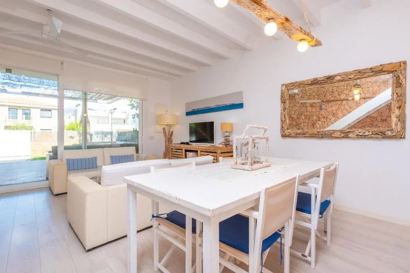 Una luminosa zona de comedor y estar con una mesa grande y puertas de vidrio.