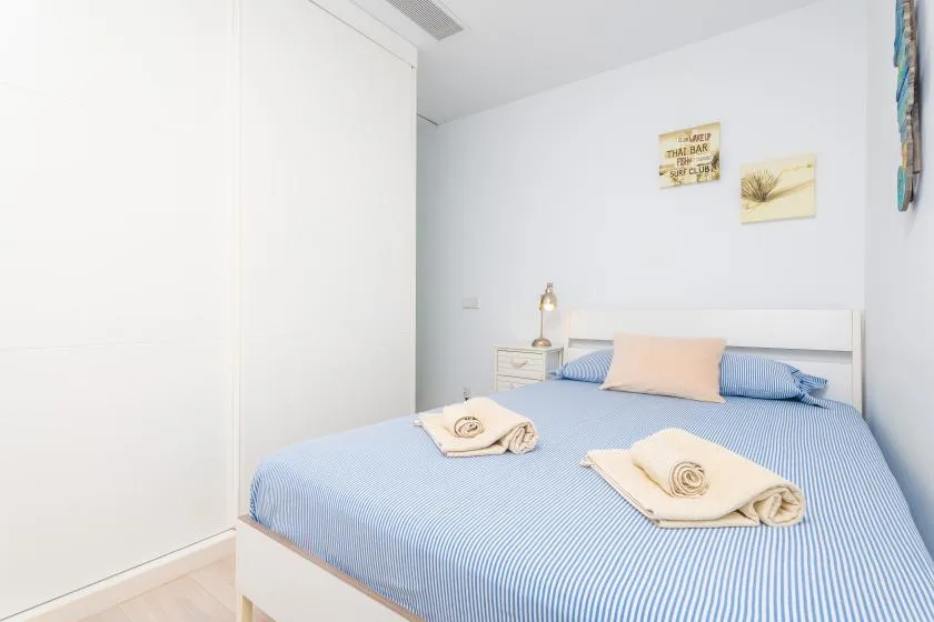 Un dormitorio con una cama de rayas azules y toallas dobladas.