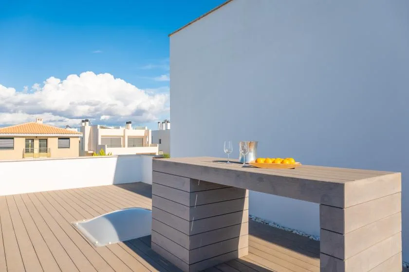 Una terraza en la azotea con una mesa de comedor y vistas a edificios cercanos.