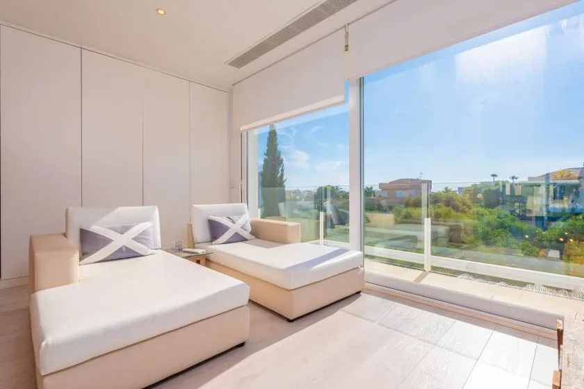 Una sala luminosa con dos divanes tapizados junto a grandes ventanales con vistas a zonas verdes.