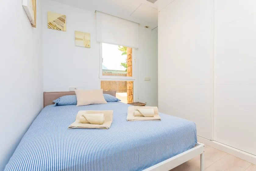Un dormitorio luminoso con una cama cubierta de azul y una ventana.