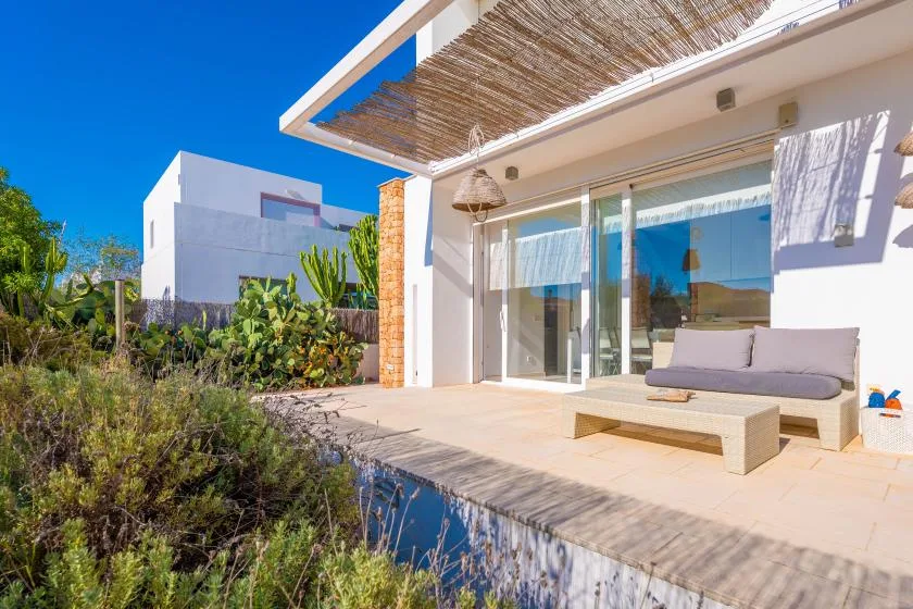 Un patio moderno con asientos al aire libre da a una pequeña piscina reflectante.