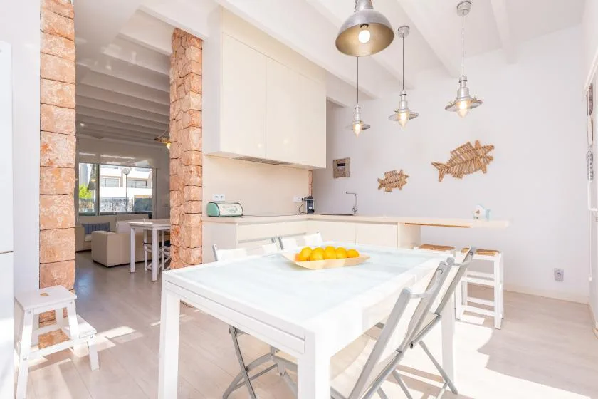 Un comedor luminoso con una mesa blanca y una encimera de cocina.