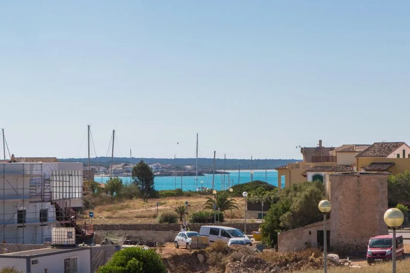 Escena de un pueblo costero con agua turquesa y edificios junto a la costa.