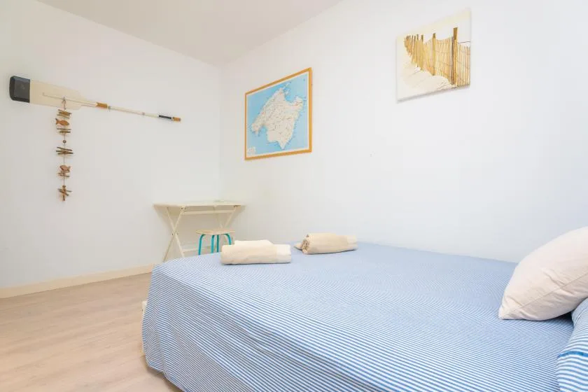 Un dormitorio con una cama cubierta de azul y cuadros en la pared.