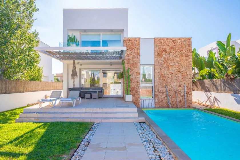 Una casa moderna se abre a una piscina, un patio y un jardín.