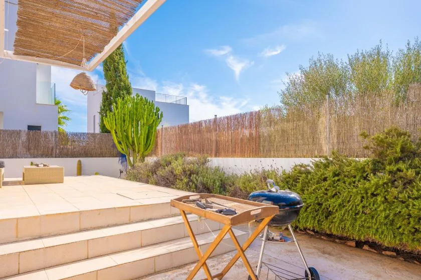 Un patio exterior con escalones de baldosas, una mesa pequeña y una parrilla.