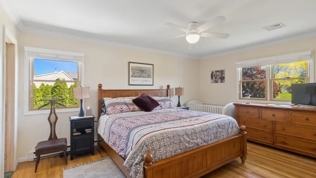 Un dormitorio luminoso con una cama de madera y ventanas grandes.