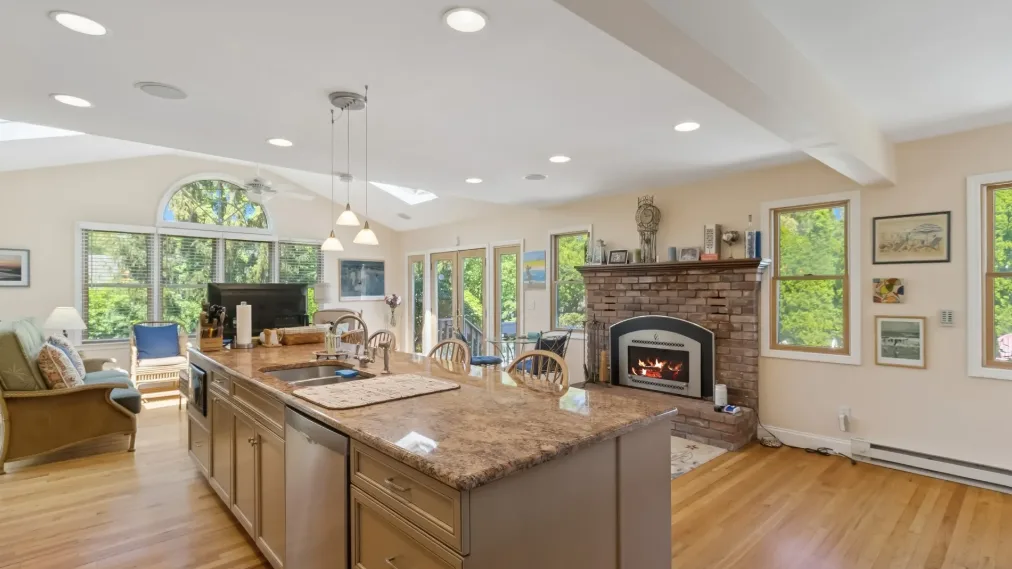 Cocina y sala de estar de planta abierta con una isla central y chimenea.