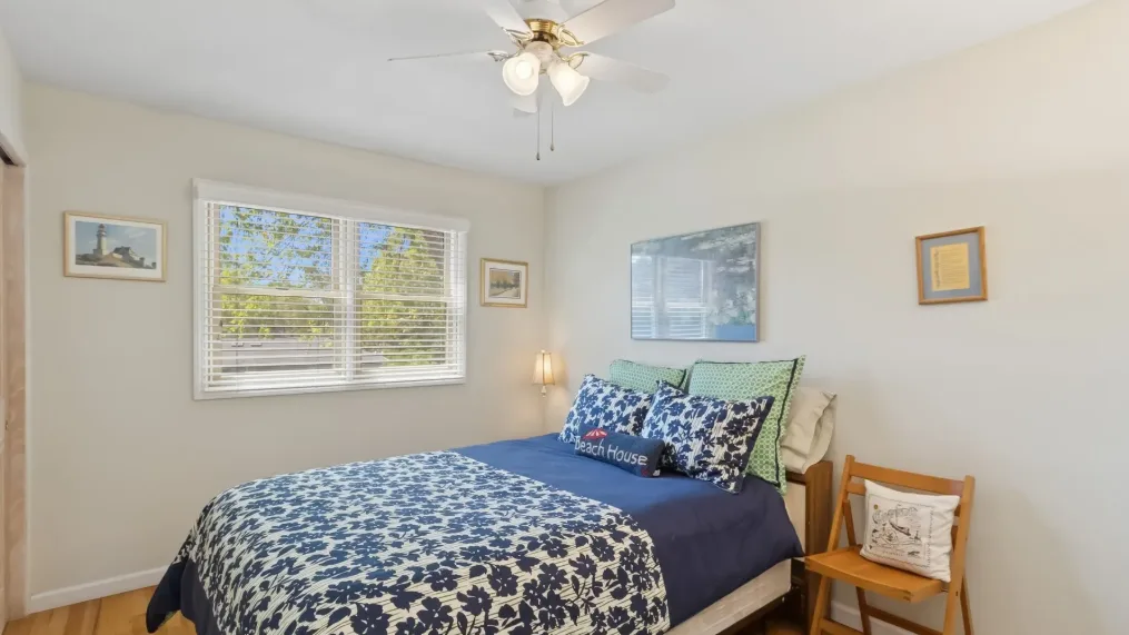 Un dormitorio con una cama cubierta con ropa de cama floral azul y una ventana.