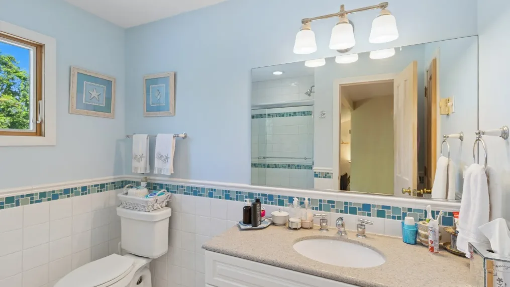 Un baño con lavabo, inodoro y un espejo grande.