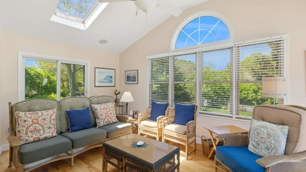 Una sala luminosa con asientos alrededor de una mesa de centro y grandes ventanas.