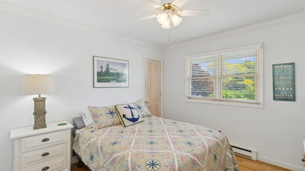 Un dormitorio con una colcha estampada y una ventana con persianas.