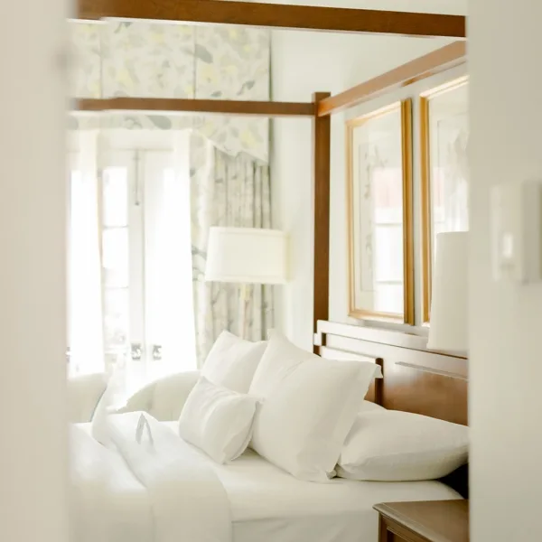 Hotel room bed and carved wooden bedposts viewed from the hallway entrance.