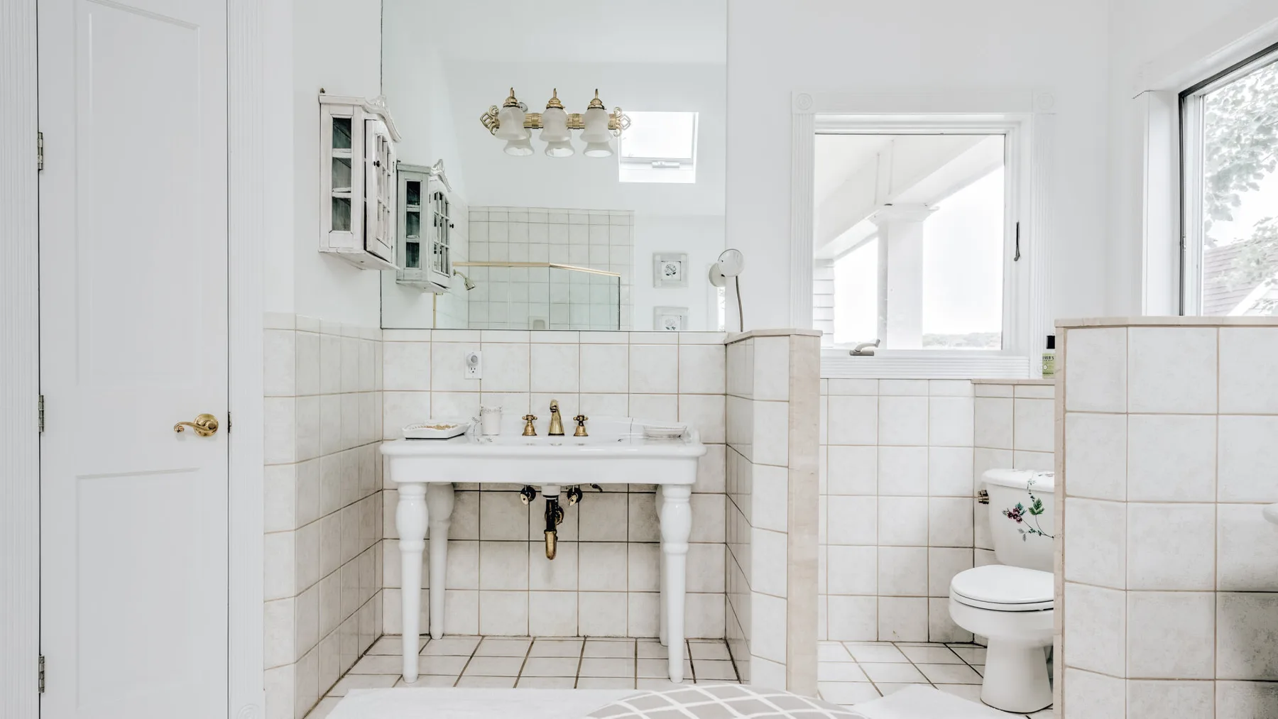 A bright tiled bathroom with a white sink and toilet.