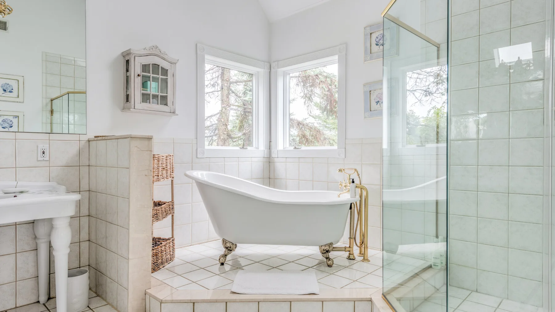 A bright bathroom features a freestanding bathtub beside a glass shower.