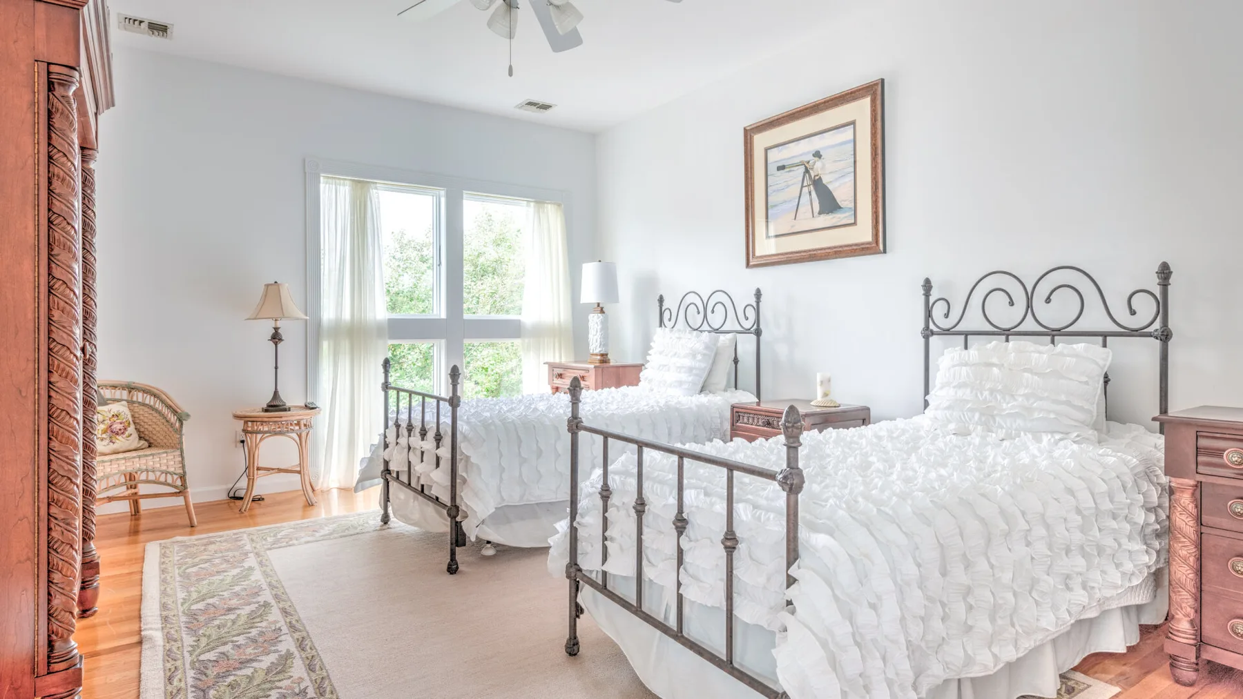 A bright bedroom with two beds, white bedding, and large windows.