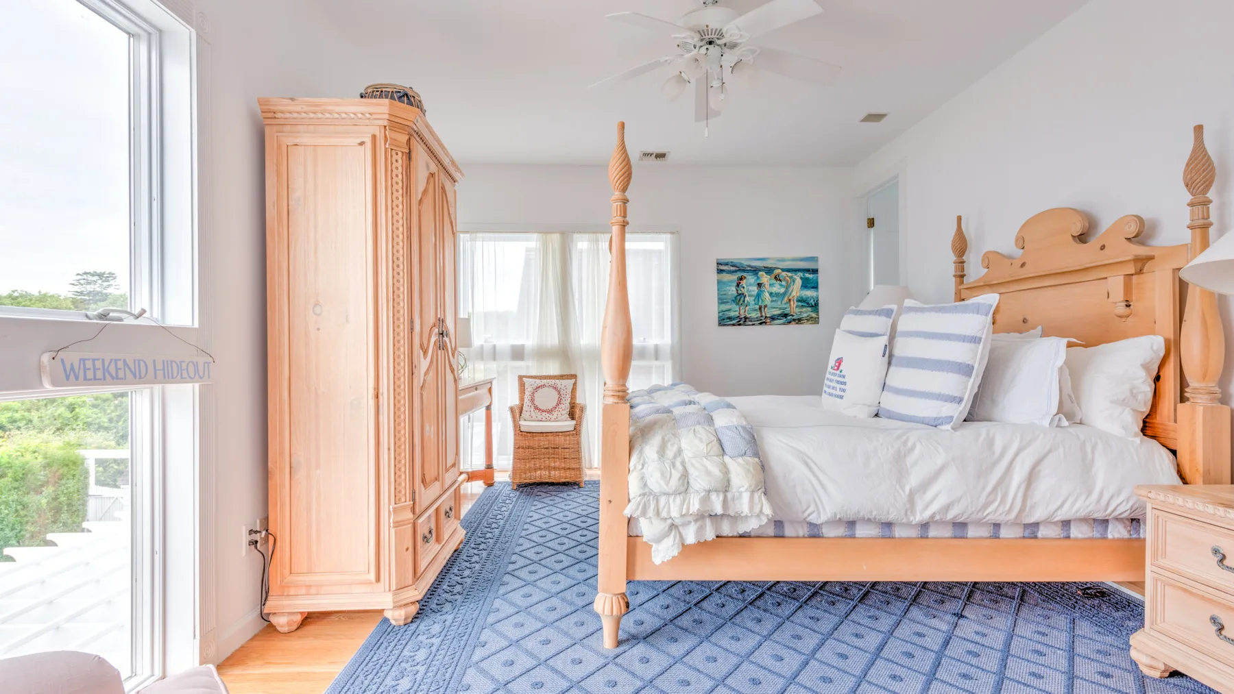A bright bedroom with a wooden bed and blue patterned carpet.